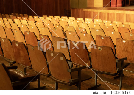 an old empty theater auditorium with old seats and a dimly lit stage an old empty theater auditorium with old seats and a dimly lit stage 133306358