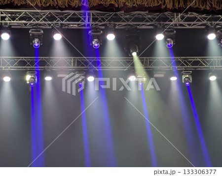 Multicolored beams of stage lighting illuminate the stage of the hall before the performance 133306377