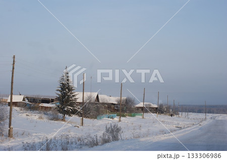 The photograph depicts old houses in a Siberian village, an old fence, and snowdrifts 133306986