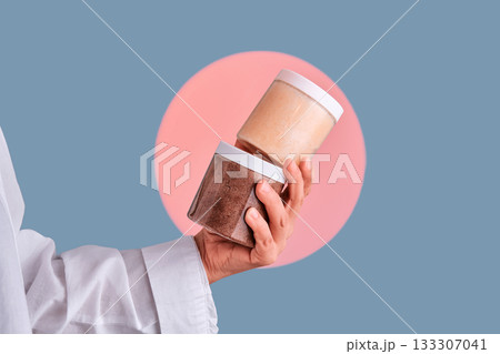 Hand holding cosmetic body scrub jars for skincare 133307041