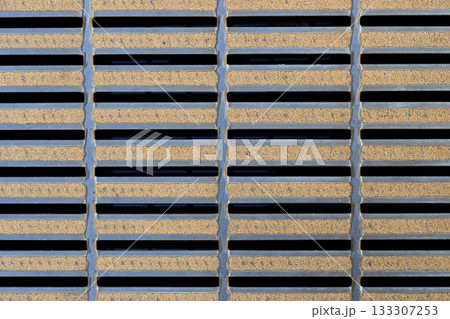 デザイン性のある金属製グレーチングのクローズアップ。格子状の側溝の蓋と規則的なパターン 133307253