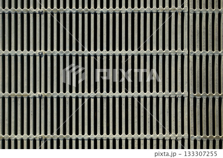 金属製グレーチングのクローズアップ。格子状の側溝の蓋の規則的なパターン 133307255