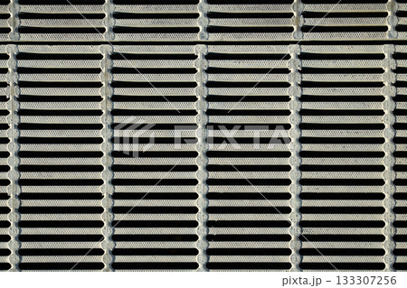 金属製グレーチングのクローズアップ。格子状の側溝の蓋の規則的なパターン 133307256