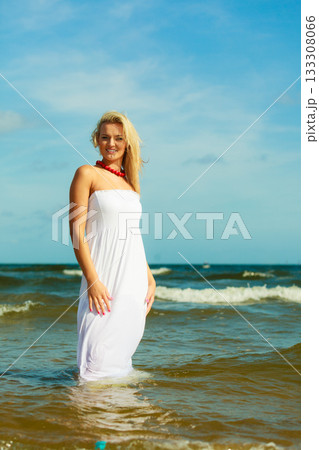 Blonde woman wearing dress walking in water 133308066