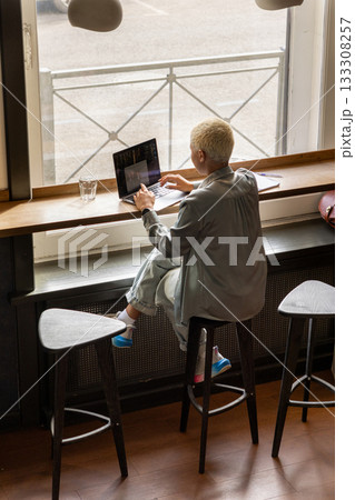 African American woman with short blond hair is sitting at a table, typing on laptop. African American woman with short blond hair is sitting at a table, typing on laptop. 133308257