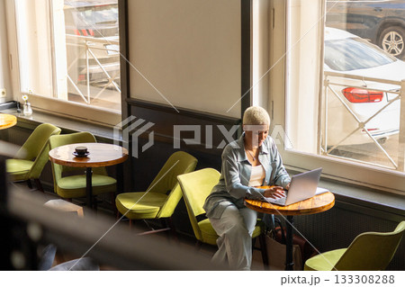 African American woman with white hair sits at desk with laptop, is surfing the Internet. female blogger. 133308288