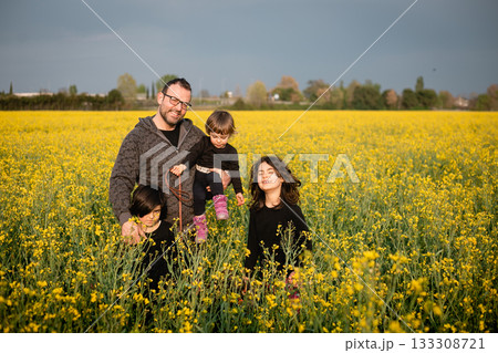 father with three children standing in a field with yellow flowers 133308721