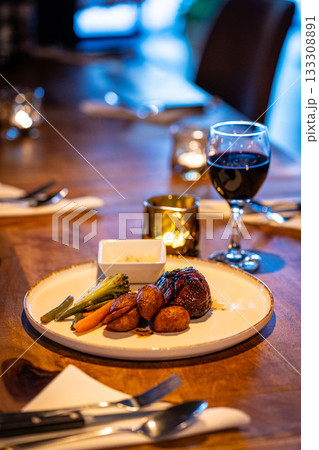Beef steak meat with vegetables and sauce served with red wine and candles 133308891