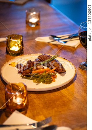 Beef steak meat with vegetables and sauce served with red wine and candles 133308901
