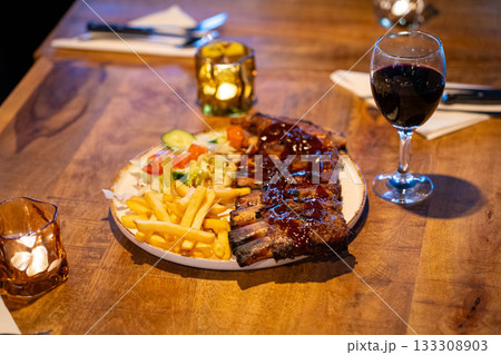 Tender grilled porterhouse or t-bone steak served with crisp golden French fries and fresh green herb salad accompanied by a BBQ or tomato ketchup sauce 133308903