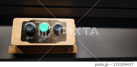 A child's hands grip a small wooden control panel with three buttons. Concepts include child development, tactile learning, technology for children, hand-eye coordination, and interactive exhibits. 133309437