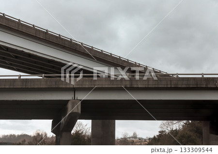 Highway overpass structure against cloudy sky in an urban setting 133309544