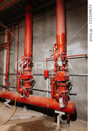 Fire sprinkler valves and red pipes in industrial plant, safety equipment, vertical view 133309673