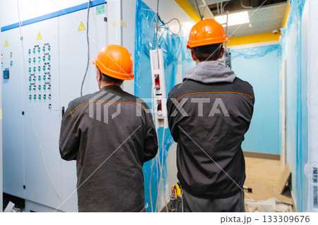 Two construction workers in hard hats inspecting electrical panels at building site Two construction workers in hard hats inspecting electrical panels at building site 133309676