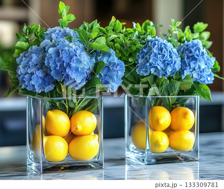 Glass vases hold vibrant blue hydrangeas and fresh lemons, citrus freshness creating fresh, bright, and creative kitchen 133309781