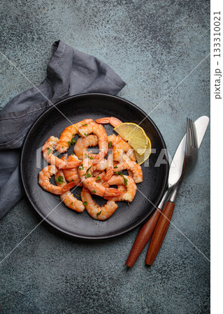 Cooked grilled shrimps lemon parsley black plate seafood appetizer black background Cooked grilled shrimps lemon parsley black plate seafood appetizer black background 133310021