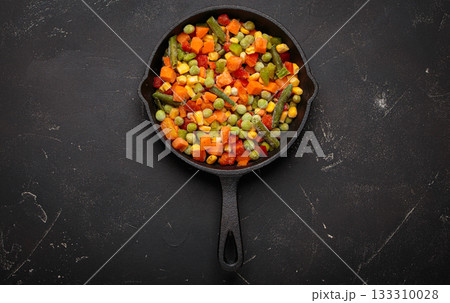 Frozen mixed vegetables cast iron skillet black background healthy cooking defrosting 133310028