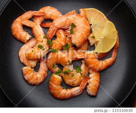 Cooked grilled shrimps lemon parsley black plate seafood appetizer black background 133310030