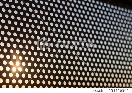 斜めから見たパンチングメタルと夕日 133310342