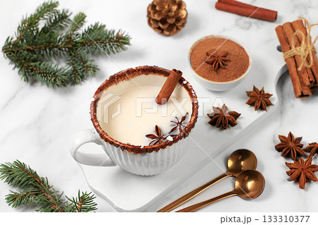 Eggnog with cinnamon, anise, and nutmeg for Christmas and the winter holidays on a marble table. A warming eggnog during the cold season, a festive arrangement for Christmas Eve Eggnog with cinnamon, anise, and nutmeg for Christmas and the winter holidays on a marble table. A warming eggnog during the cold season, a festive arrangement for Christmas Eve 133310377