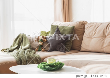 Cozy Living Room with Crocheted Reindeer Toy on Sofa and Christmas Holiday Candle Decor on Table Cozy Living Room with Crocheted Reindeer Toy on Sofa and Christmas Holiday Candle Decor on Table 133310480
