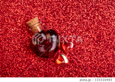 Heart-Shaped Glass Bottle with Red Liquid on Glittery Background for Valentines Day Celebration Heart-Shaped Glass Bottle with Red Liquid on Glittery Background for Valentines Day Celebration 133310493