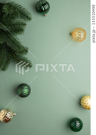 Fir Tree Branch with Green and Golden Christmas Ornaments on Green Background in Festive Flat Lay Fir Tree Branch with Green and Golden Christmas Ornaments on Green Background in Festive Flat Lay 133310498