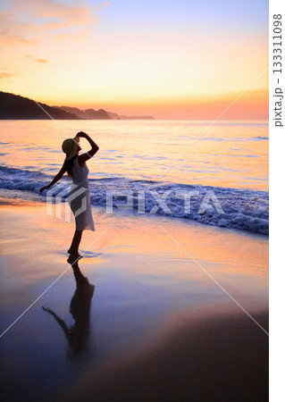 海に沈む夕日と女性のシルエット 133311098