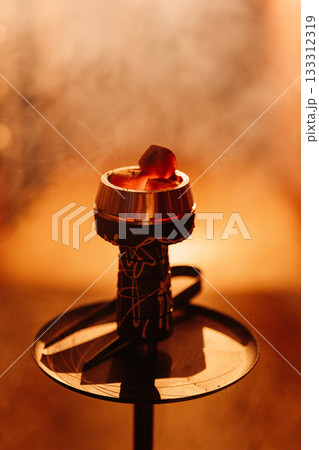 Hookah bowl with glowing coal and drifting smoke in warm bokeh bar light Hookah bowl with glowing coal and drifting smoke in warm bokeh bar light 133312319