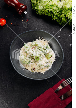 Broccoli in creamy parmesan sauce on dark plate, overhead, restaurant style 133312325