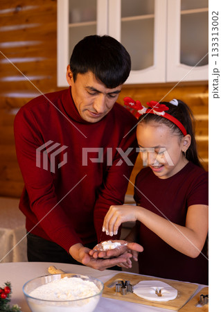 Father and daughter are happily sprinkling powdered sugar on Christmas cookies Father and daughter are happily sprinkling powdered sugar on Christmas cookies 133313002