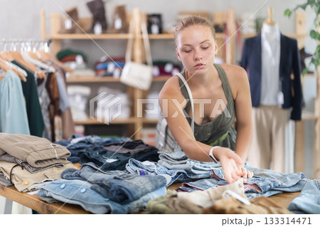 Woman standing in the store and choosing pants and shorts 133314471