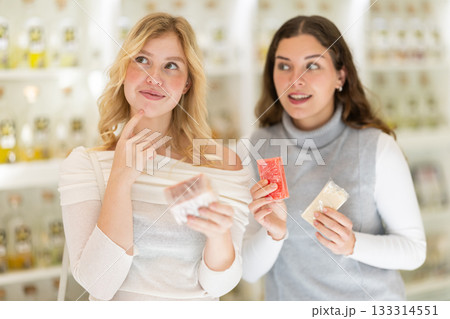 Female consultant helps girl choose craft soap at beauty shop 133314551