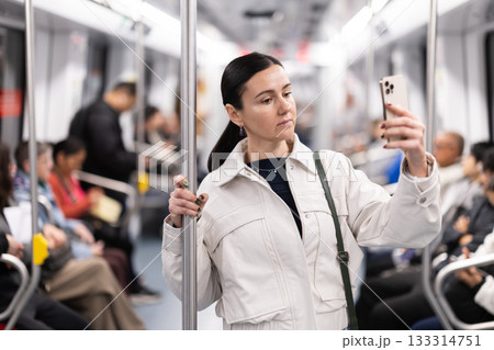 In the subway car, woman with mobile phone makes a selfie or scans QR code 133314751