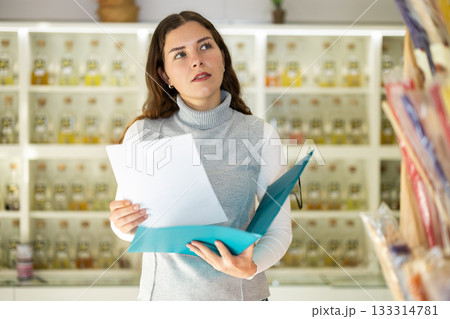 Girl seller with paper document make inventory in perfume store Girl seller with paper document make inventory in perfume store 133314781