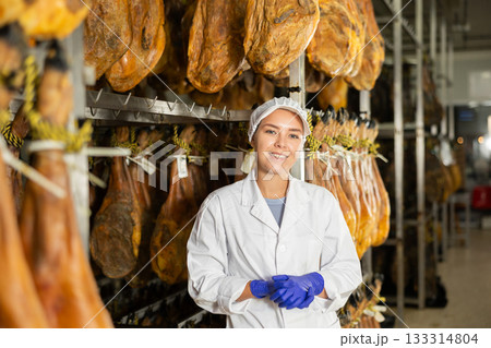 Satisfied female worker at jamon factory shows off finished jamon 133314804