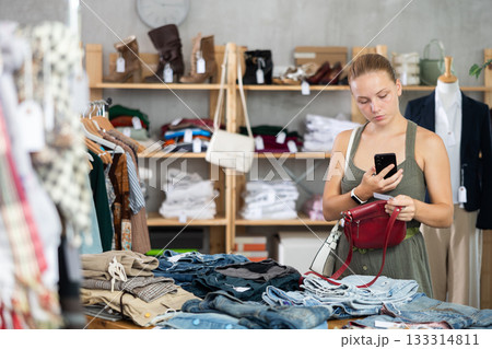 Teenage girl scanning QR-code on handbag in clothing store Teenage girl scanning QR-code on handbag in clothing store 133314811