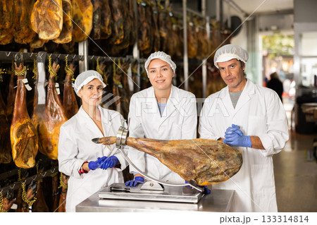 Staff of hamon manufacturing workshop presents product using jamonero 133314814