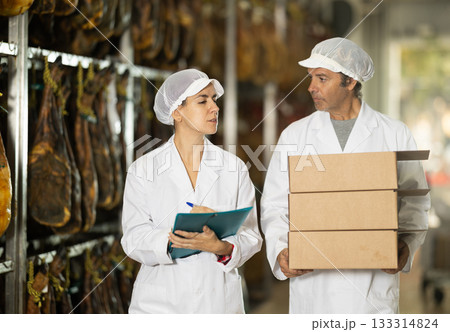 Woman head of department communicates with male porter at ham production factory 133314824
