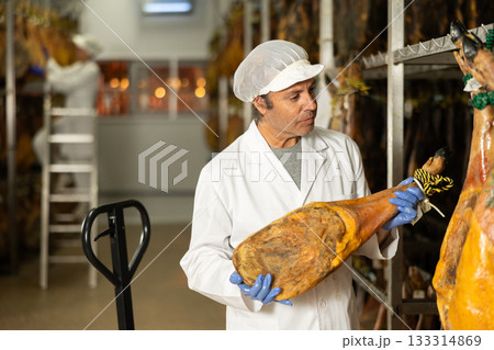 Man employee checks jamon. Quality control 133314869