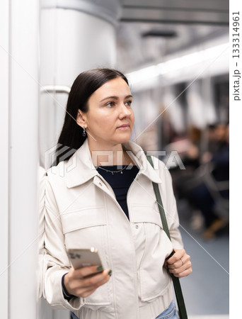 Woman with phone stand in metro carriage. 133314961