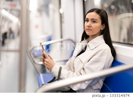 Woman in metro carriage points phone camera at an information board Woman in metro carriage points phone camera at an information board 133314974