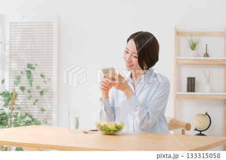 スマホでサラダの写真を撮る女性 133315058