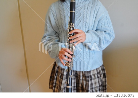 淡いブルーのニットを着た子どもがクラリネットを構えている手元の写真。 淡いブルーのニットを着た子どもがクラリネットを構えている手元の写真。 133316075