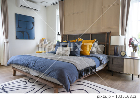 Interior of yellow and blue pillow on cozy modern bedroom with carpet and side table lamp. Interior of yellow and blue pillow on cozy modern bedroom with carpet and side table lamp. 133316812