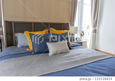 Interior of yellow and blue pillow on cozy modern bedroom with carpet and side table lamp. 133316814