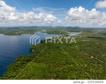 Tropical coastline showing mangrove forest and nearby coastal town with mountains in the distance. Siargao, Philippines. Tropical coastline showing mangrove forest and nearby coastal town with mountains in the distance. Siargao, Philippines. 133316858