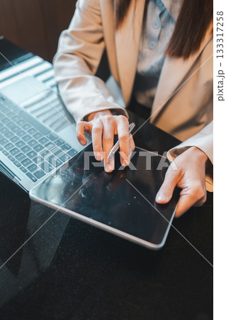 A business professional using a tablet and laptop, showcasing modern technology in a professional office environment. 133317258