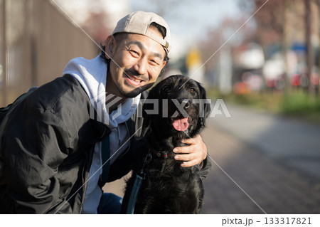 愛犬と散歩を楽しむ男性の動物とのコミュニケーションシーン　躾や訓練、仲良しや信頼のイメージカメラ目線 133317821