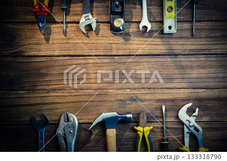 Hand tool collection is being displayed in flat-lay wood workbench, featuring hammer and wrenches 133318790